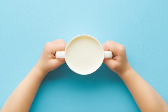 흰 우유가 들어있는 컵을 잡고 있는 어린이