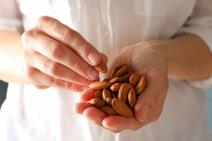 A person enjoying a handful of almonds.